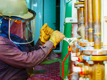 Commercial plumber working on tightening a wrench during a plumbing maintenance project